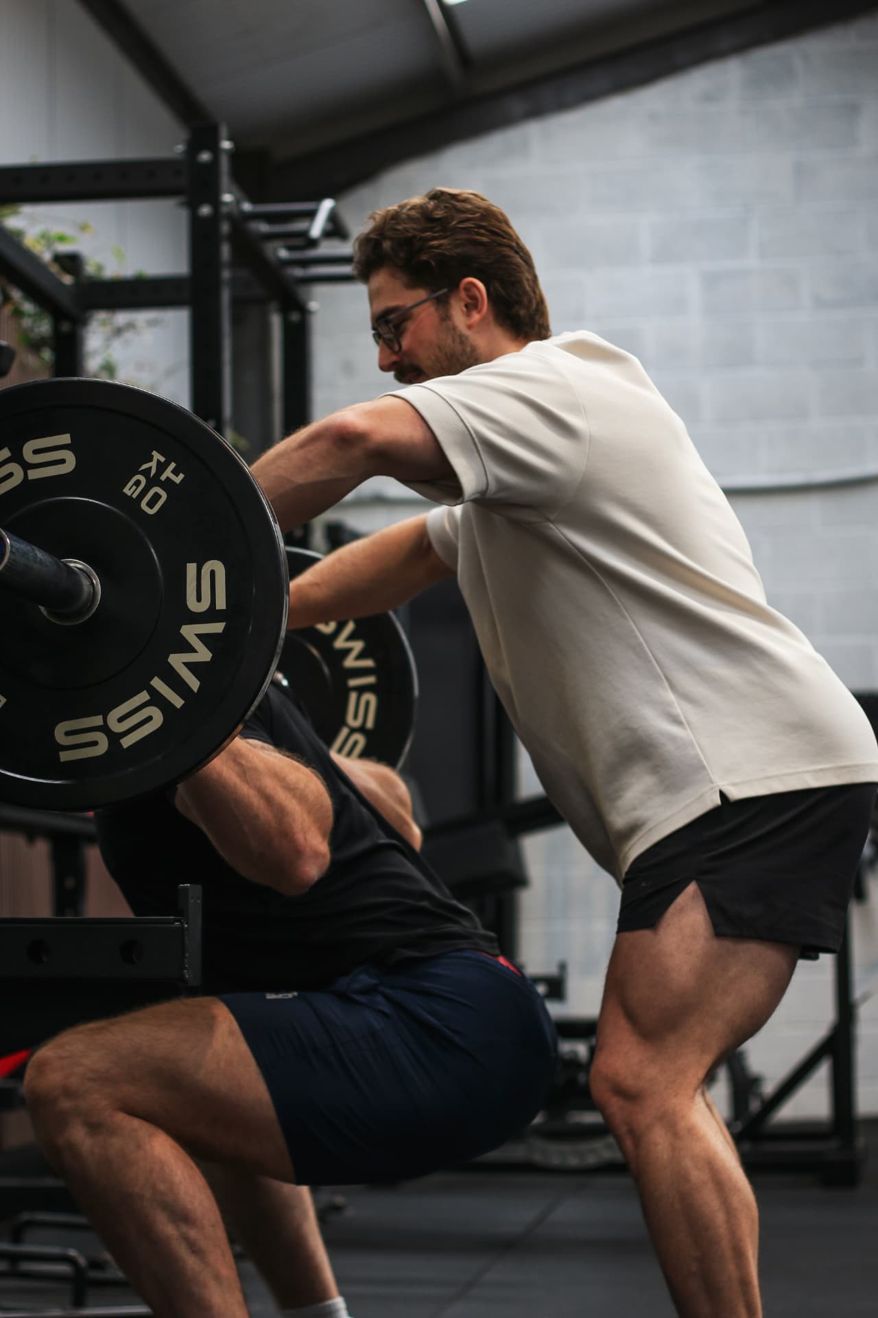 Coach spotting a client during a barbell squat at Proteus